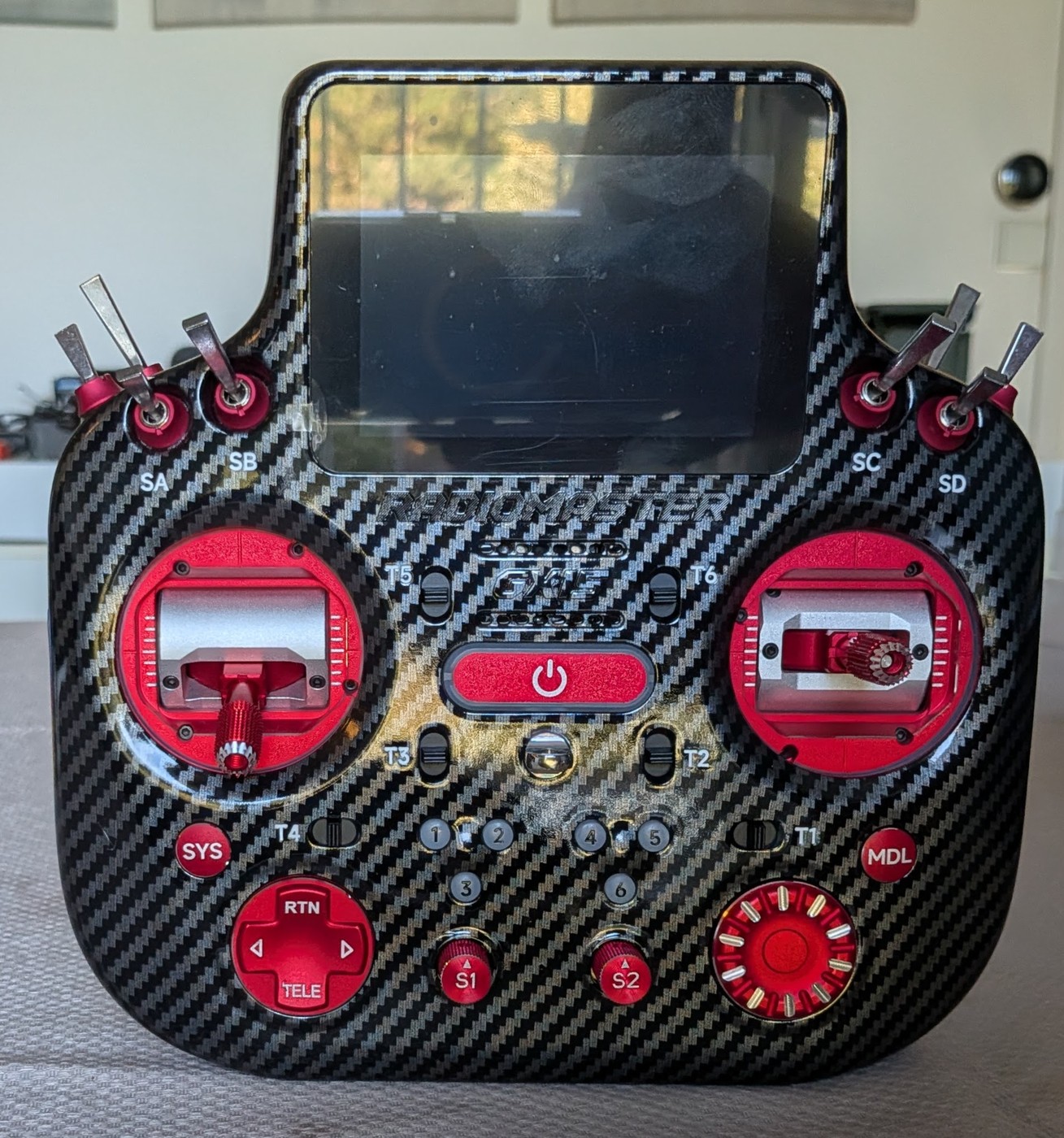 La RadioMaster GX15 MAX vue de face, finition carbone et pièces rouges anodisées